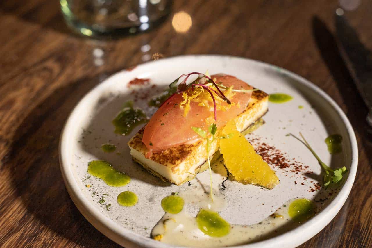 A plated starter with orange segments and herb oil