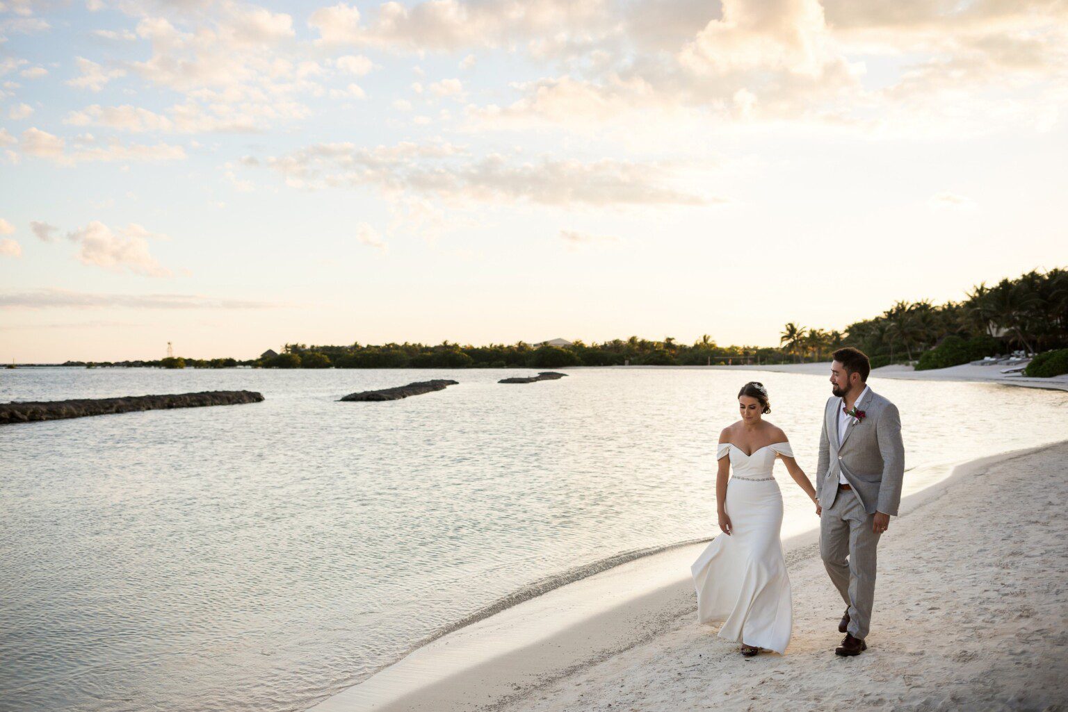 A couple walking on the beach at dusk after their wedding