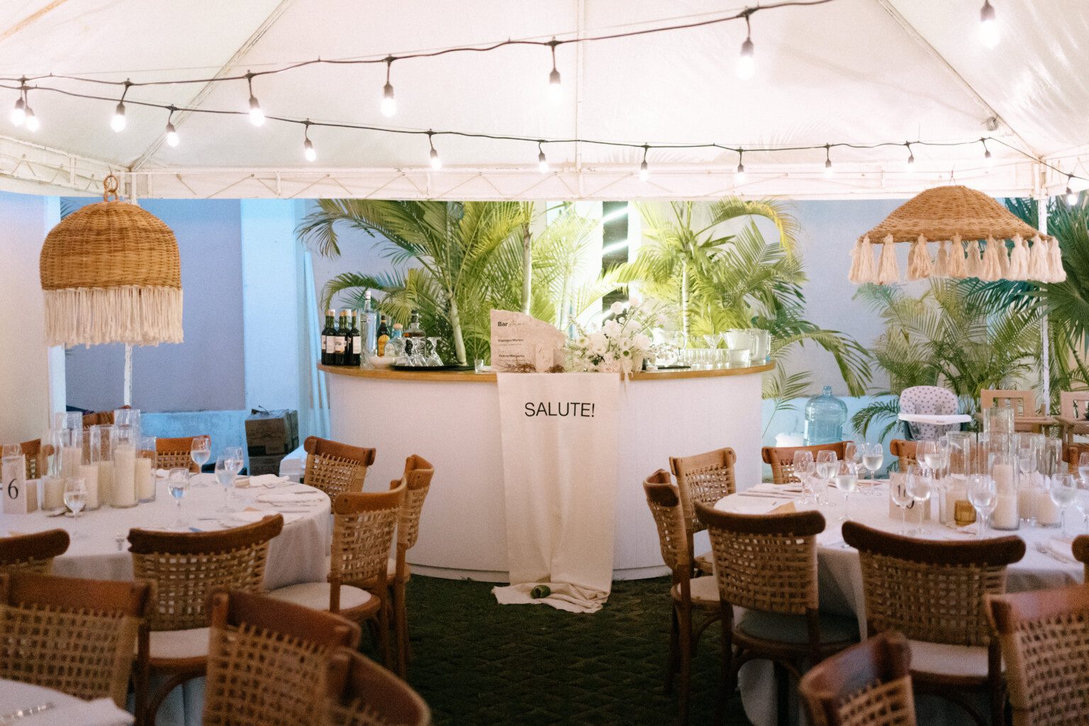 Round reception tables set under a white tent in a hacienda garden
