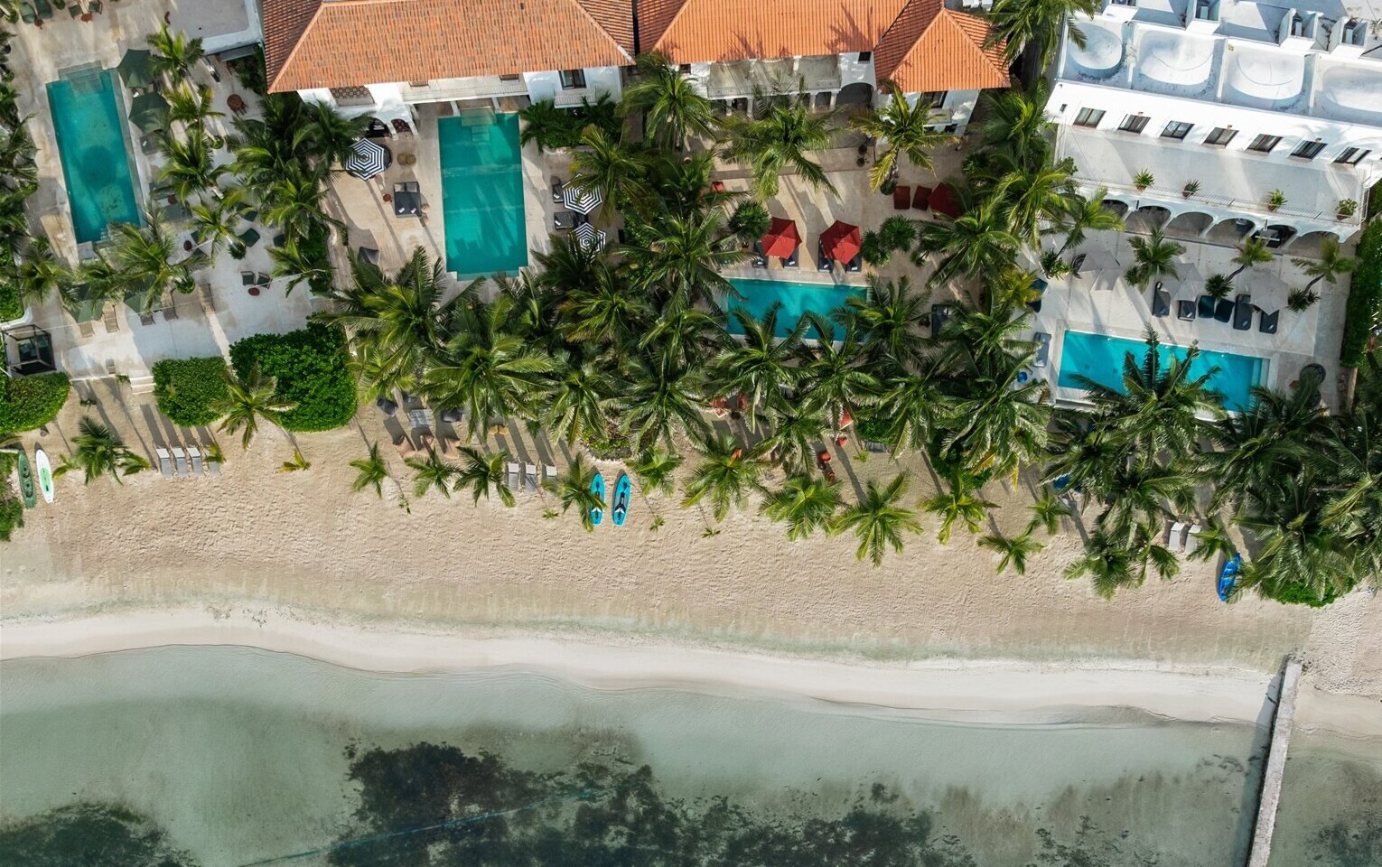 Aerial view of luxury beachfront villas in Puerto Aventuras with private pools and palm trees