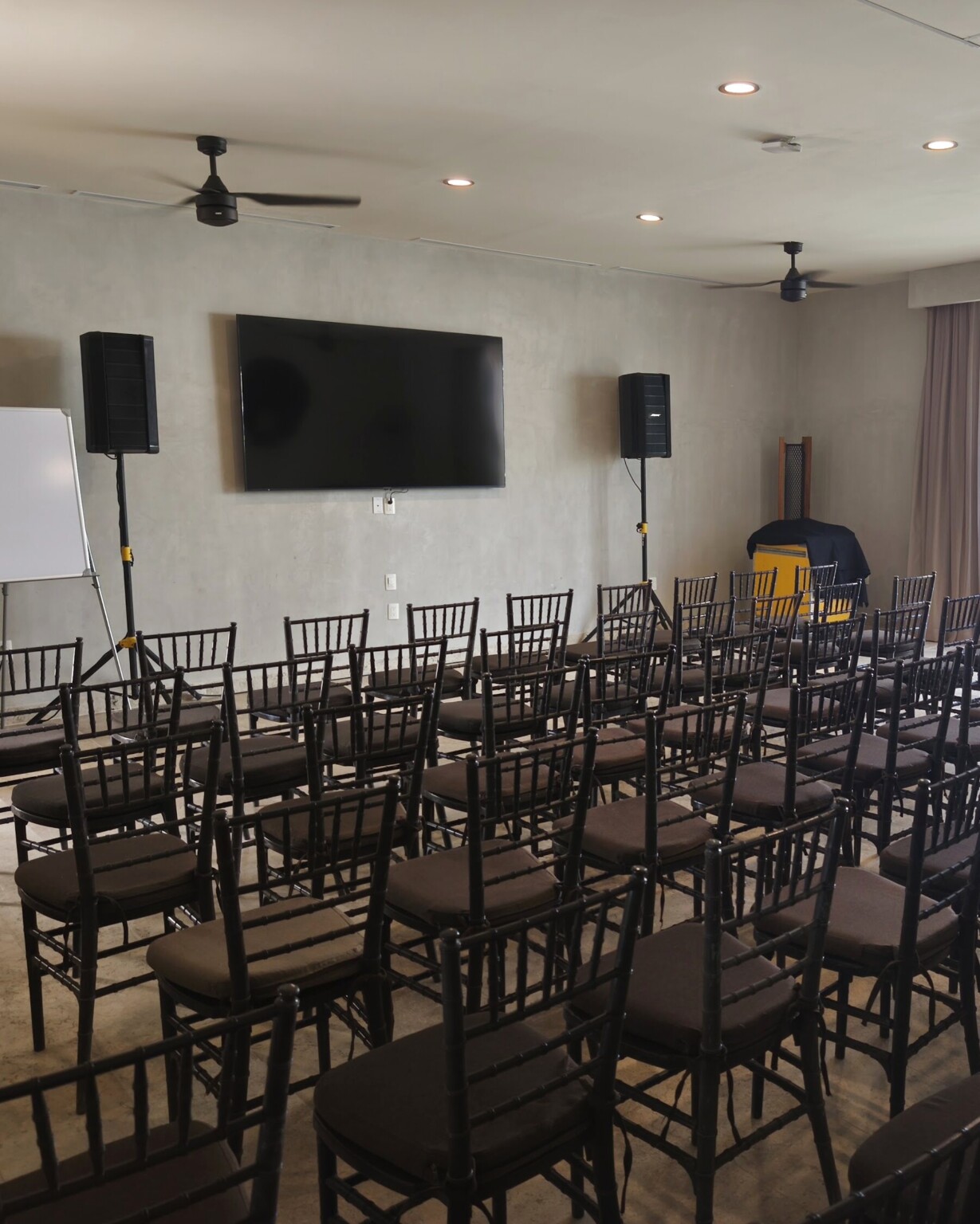 The games room at Hacienda Jaguar set theatre-style for a meeting: rows of chairs facing a large screen, speakers and a flip chart