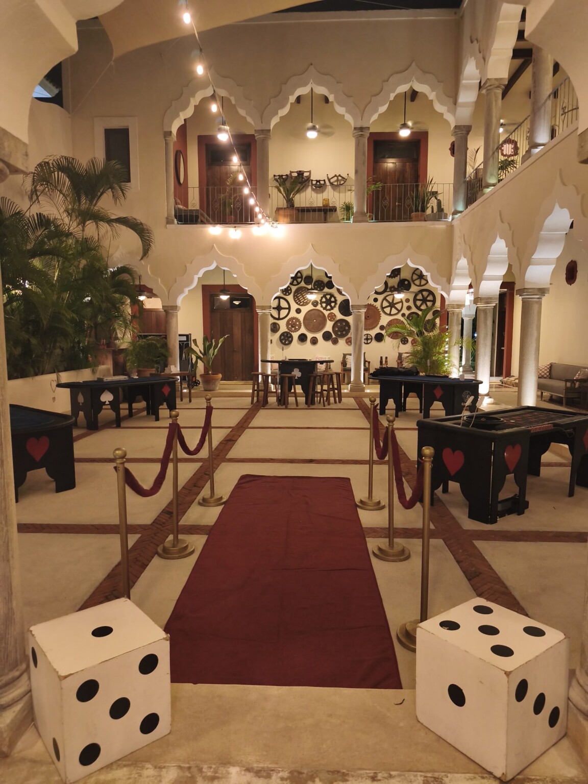 A hacienda courtyard set for casino night: red carpet, velvet ropes and giant dice