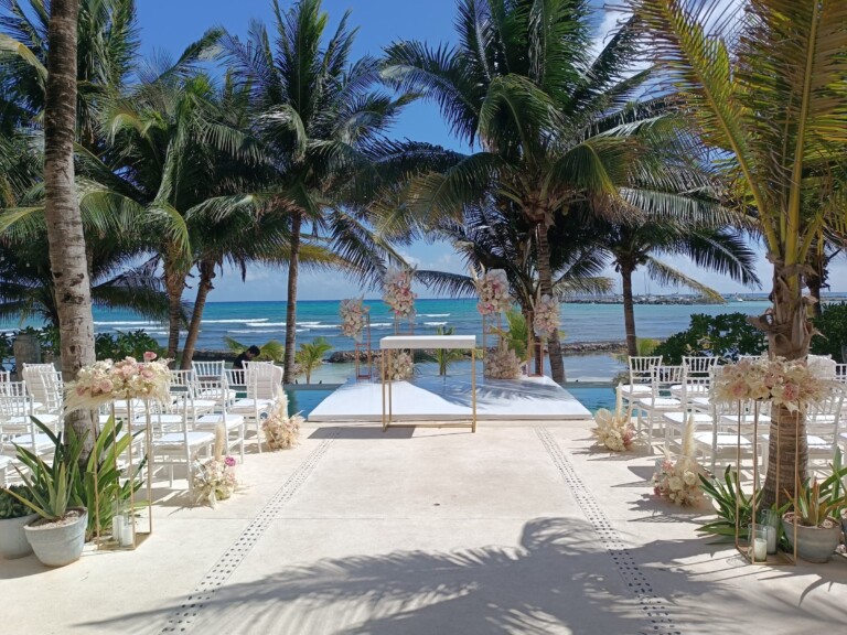 A white ceremony aisle between floral stands, opening onto the turquoise sea at Hacienda Del Mar