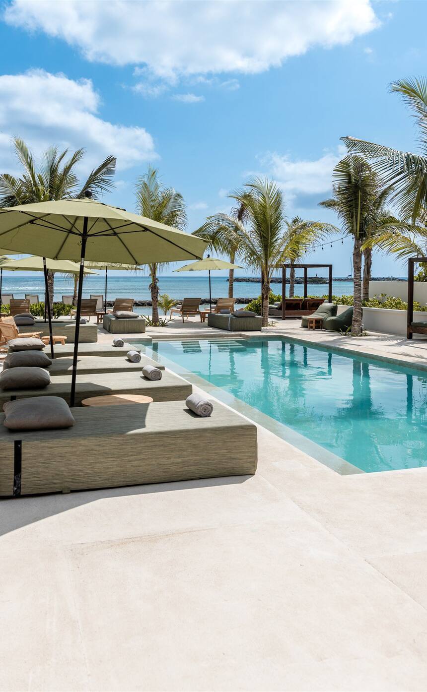 The long pool at Hacienda Jaguar, umbrellas and loungers beside it, the sea beyond