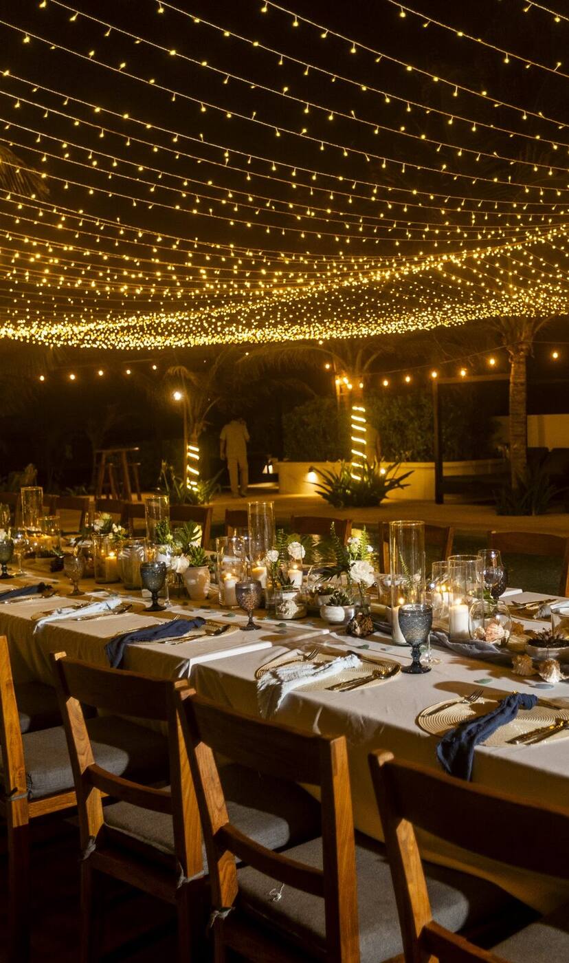 A long dinner table set under golden string lights at Hacienda Jaguar, at night